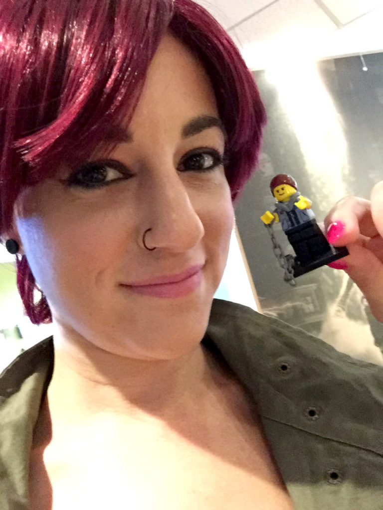 Me holding a tiny, handmade, LEGO minifig of Delsin Rowe.